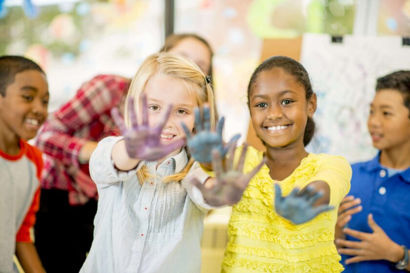 Two girls showing off their finger painted hands.